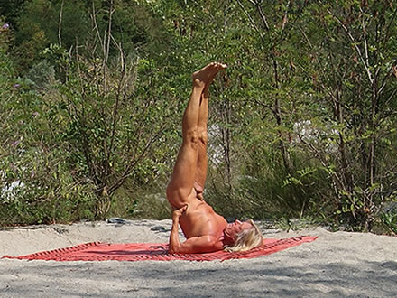 Yogi führt die Haltung der physischen Umkehrung nackt auf einer Sandbank aus